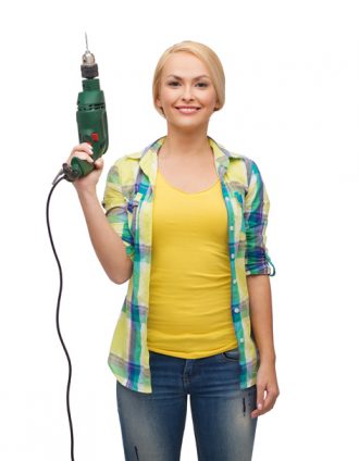 repair, construction and maintenance concept - smiling woman with drill machine